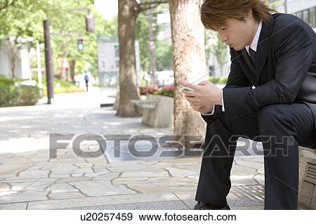 Stock Photo - Young businessman looking at mobile phone. Fotosearch