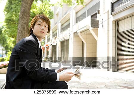 Stock Photo - Young businessman reading newspaper. Fotosearch
