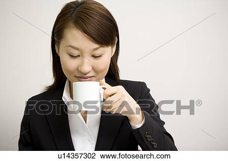 Stock Image - Young businesswoman drinking a cup of coffee. Fotosearch