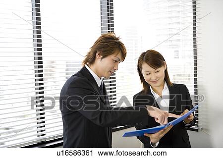 Young man and woman looking at document View Large Photo Image Stock Image - Young man and woman looking at document. Fotosearch