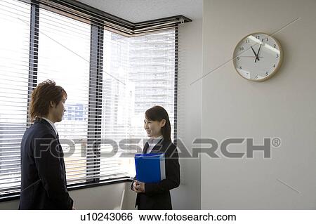 Stock Photograph - Young man and woman talking in office. Fotosearch