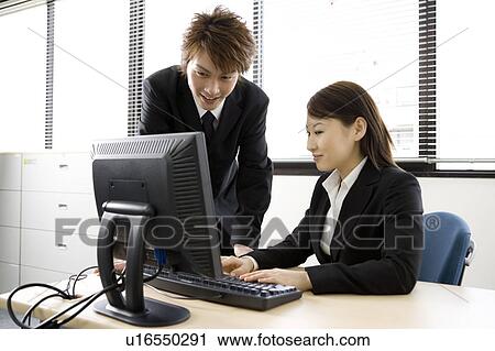 Stock Image - Young man and woman working in office. Fotosearch