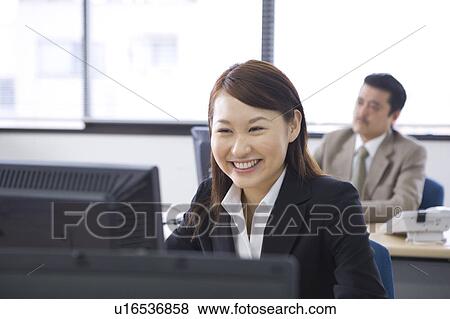 Stock Photo - Young woman working in office. Fotosearch