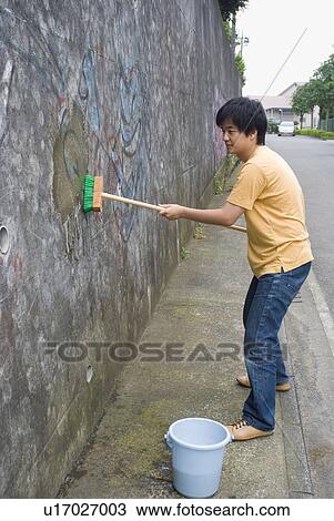 Young man cleaning graffiti on wall View Large Photo Image Stock Image - Young man cleaning graffiti on wall. Fotosearch