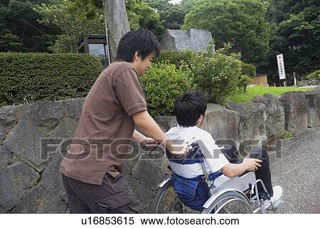 Young man pushing man on wheelchair View Large Photo Image Stock Photography - Young man pushing man on wheelchair. Fotosearch