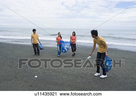 Stock Image - Young people cleaning beach. Fotosearch
