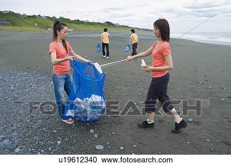 Stock Image - Young people cleaning beach. Fotosearch