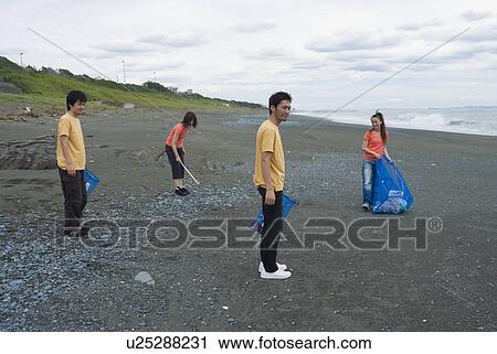 Stock Image - Young people cleaning beach. Fotosearch