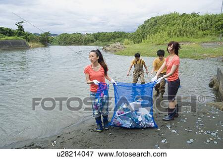 Stock Photo - Young people cleaning river. Fotosearch