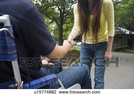 Young woman shaking hands with a man on wheelchair View Large Photo Image Stock Image - Young woman shaking hands with a man on wheelchair. Fotosearch
