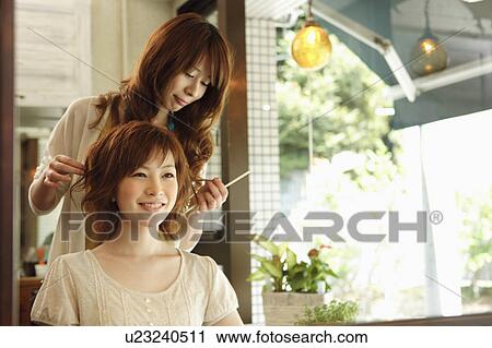 Stock Image - Hair dresser styling young woman's hair. Fotosearch