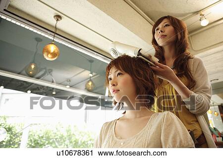 Stock Image - Hairdresser drying woman's hair. Fotosearch