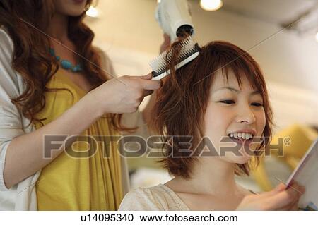 Stock Image - Hairdresser drying woman's hair. Fotosearch