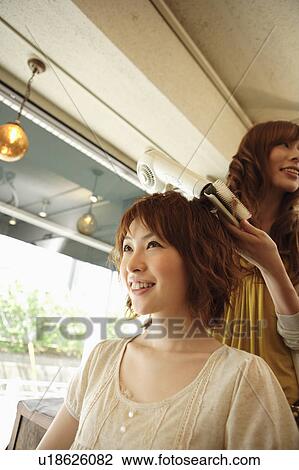 Stock Image - Hairdresser drying woman's hair. Fotosearch