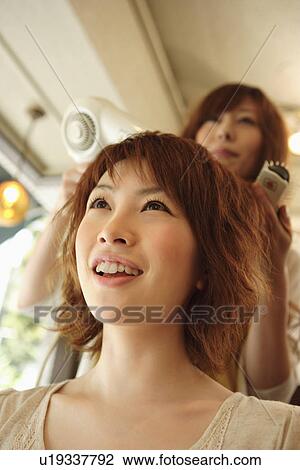 Stock Image - Hairdresser drying woman's hair. Fotosearch