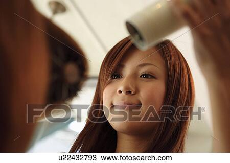 Stock Image - Hairdresser drying woman's hair. Fotosearch