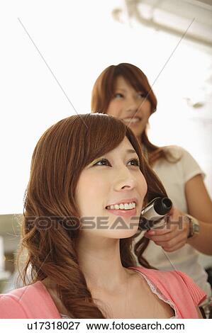 Stock Photo - Hairdresser drying woman's hair. Fotosearch