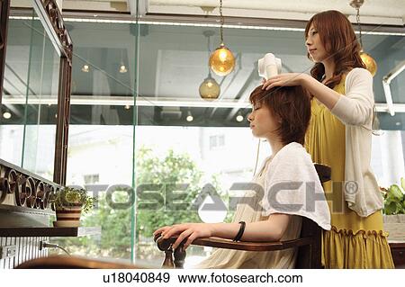 Stock Photo - Hairdresser drying woman's hair. Fotosearch