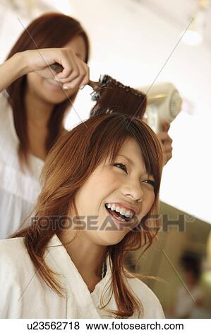 Stock Photo - Hairdresser drying woman's hair. Fotosearch