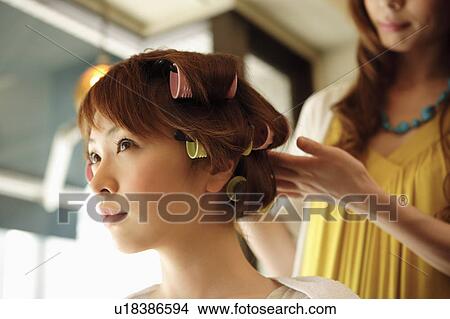 Picture - Hairdresser putting curlers in customer's hair. Fotosearch