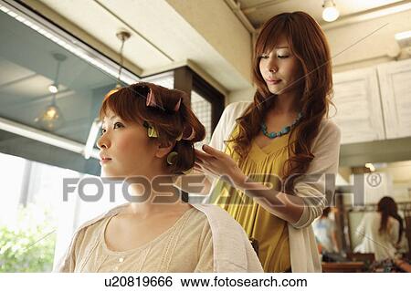 Stock Photograph - Hairdresser putting curlers in customer's hair. Fotosearch