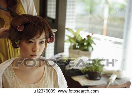 Stock Photo - Young woman having hair curled. Fotosearch