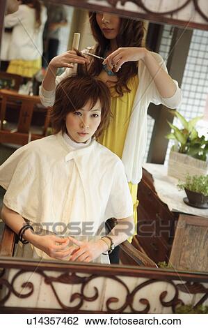 Stock Image - Young woman having hair cut. Fotosearch