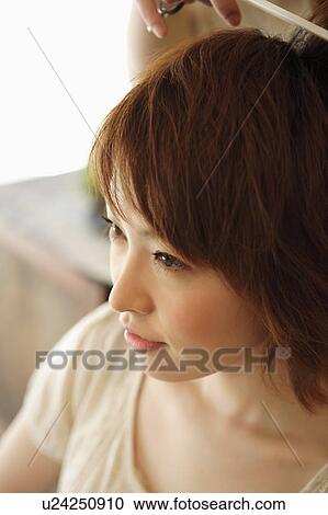 Stock Image - Young woman having hair cut. Fotosearch