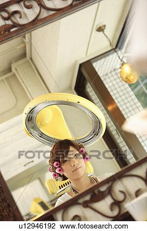 Stock Image - Young woman having hair permed. Fotosearch