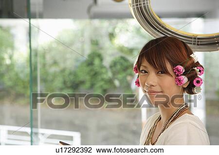 Stock Image - Young woman having hair permed. Fotosearch