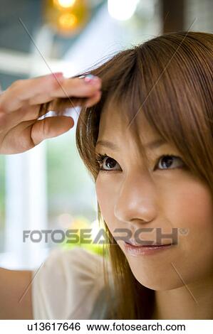 Stock Photograph - Young woman touching bangs. Fotosearch