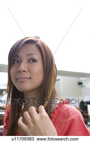 Stock Image - Young woman touching hair. Fotosearch