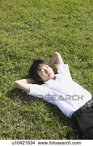 Schoolboy sleeping in grass field View Large Photo Image Picture - Schoolboy sleeping in grass field. Fotosearch