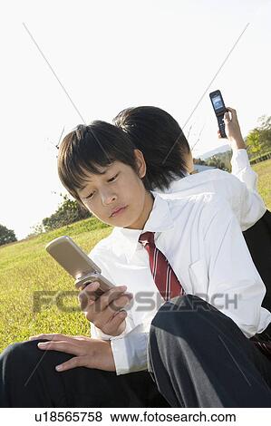 Two schoolboys looking at mobile phones View Large Photo Image Stock Photo - Two schoolboys looking at mobile phones. Fotosearch