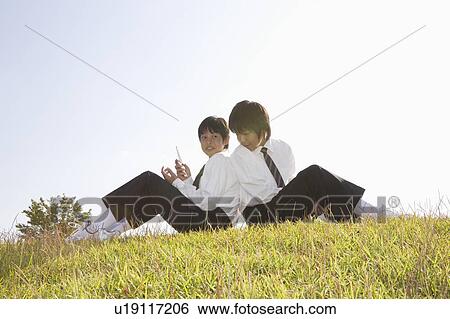Two schoolboys looking at mobile phones View Large Photo Image Stock Photograph - Two schoolboys looking at mobile phones. Fotosearch