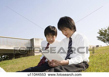 Stock Image - Two schoolboys reading book. Fotosearch