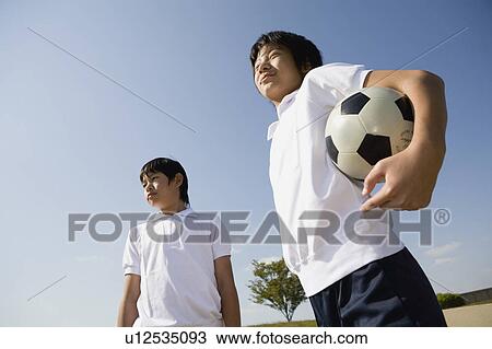 Two schoolboys standing with soccer ball View Large Photo Image Stock Image - Two schoolboys standing with soccer ball. Fotosearch