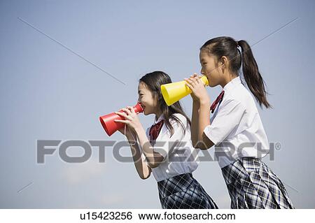 Stock Photograph - Two schoolgirls cheering with megaphones. Fotosearch