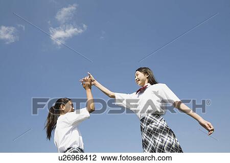 Two schoolgirls doing high-fives View Large Photo Image Stock Image - Two schoolgirls doing high-fives. Fotosearch