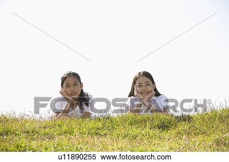Two schoolgirls lying in grass field View Large Photo Image Stock Photography - Two schoolgirls lying in grass field. Fotosearch