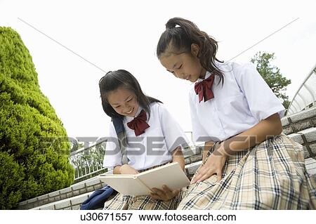 Two schoolgirls reading book View Large Photo Image Stock Photo - Two schoolgirls reading book. Fotosearch