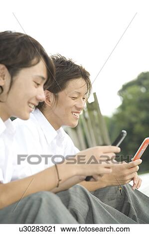 Two teenage boys looking at mobile phones View Large Photo Image Stock Image - Two teenage boys looking at mobile phones. Fotosearch
