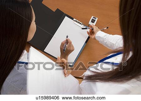 Stock Photograph - Two young women looking at document. Fotosearch