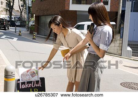 Stock Photo - Two young women looking at menu. Fotosearch