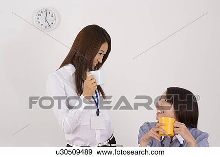Stock Photo - Two young women talking in office. Fotosearch