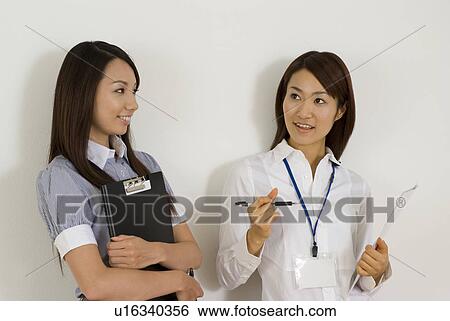 Two young women talking View Large Photo Image Stock Photograph - Two young women talking. Fotosearch