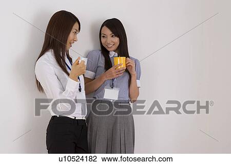 Two young women talking with cup of coffee View Large Photo Image Stock Image - Two young women talking with cup of coffee. Fotosearch