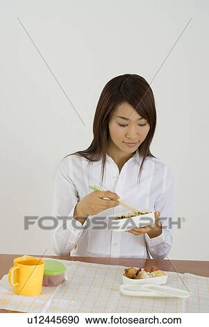 Stock Image - Young woman eating lunch. Fotosearch