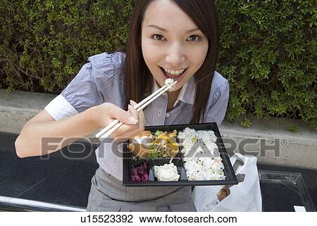 Stock Image - Young woman eating lunch. Fotosearch