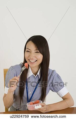 Stock Photo - Young woman eating lunch. Fotosearch